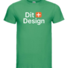Grøn T-shirt viser teksten "Dit + Design". Den hænger i et neutralt, hvidt rum, uden synlige detaljer i omgivelserne.