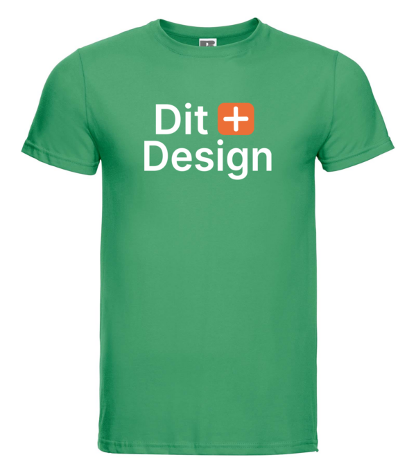 Grøn T-shirt viser teksten "Dit + Design". Den hænger i et neutralt, hvidt rum, uden synlige detaljer i omgivelserne.
