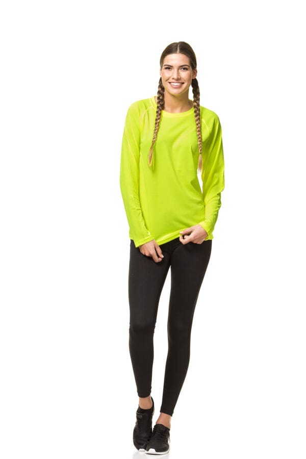 000450_Go_Sport_LS_02 Kvinde med to fletninger, iført en neongrøn trøje og sorte bukser, står og smiler mod kameraet i et hvidt studie.