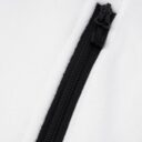 Sort lynlås på en hvid beklædningsgenstand, lynlåsen er lukket.