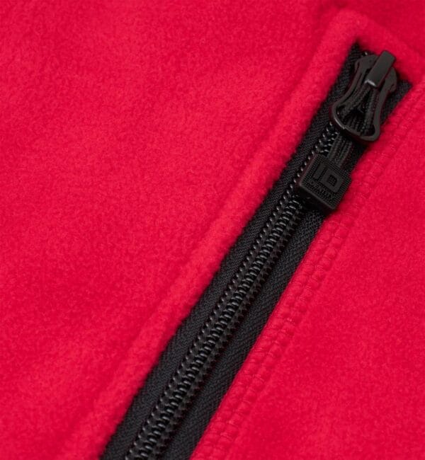 0805_330_pack_5 Sort lynlås, delvist åben, på en rød fleecejakke.
