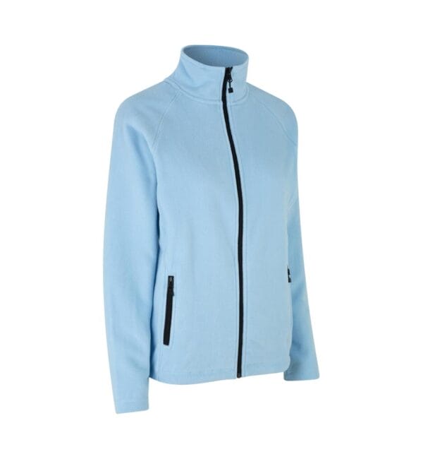 0805_700_pack_1 En lyseblå fleecejakke med sort lynlås i midten og ved sidelommerne. Jakken står oprejst med et høj hals, mod en hvid baggrund.