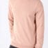 Mand iført beige sweatshirt med lange ærmer står med hænderne i lommerne af sorte bukser mod en hvid baggrund.