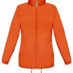 En orange jakke med lynlås og høj krave, hænger i en minimalistisk, neutral baggrund. Den har snoretræk i bunden og elastiske manchetter på ærmerne.