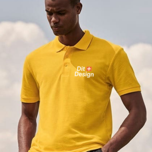 Person iført gul polo står udendørs; på trøjen står teksten "Dit + Design" i hvid skrift. Baggrunden er en delvist skyet himmel.