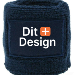 Mørkeblå armbånd med teksten "Dit+Design" på et rektangulært skilt på forsiden. Objekter omkring det er ikke synlige.
