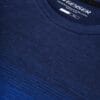 En mørkeblå t-shirt med mærket GEYSER. Tekst på mærket: MOISTURE TRANSFERRING & ANTI BACTERIAL FUNCTION, MEN'S STYLE 217.024, QUICK DRY, SMALL. T-shirten ligger fladt mod en ensfarvet baggrund.