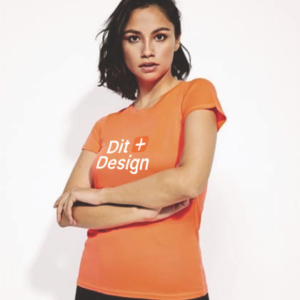 Person iført en orange T-shirt med teksten "Dit Design" trykt foran, står med armene over kors. Baggrunden er hvid og ensartet.