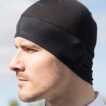 Manden bærer en sort hue og kigger til venstre. Han har kort skæg og er iført en hvid jakke. Baggrunden er en sløret natur og himmel.