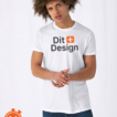 Ung mand iført en hvid T-shirt med teksten "Dit Design" står med armene krydsede over brystet, på en neutral hvid baggrund.