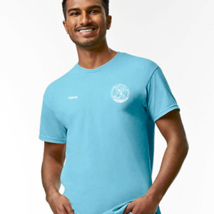 En person iført en lyseblå T-shirt smiler, stående med hænderne i lommerne på en hvid baggrund. Der er intet tekst på billedet.
