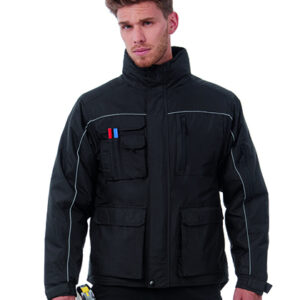 Mand står iført en sort arbejdsjakke med flere lommer og reflekterende detaljer. Han holder værktøj i hånden. Hvid baggrund uden andre genstande.