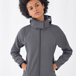 En person iført en grå jakke står med hænderne i lommerne. Jakken har en høj krave med lynlås. Baggrunden er enkel og hvid.