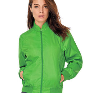 Person iført en grøn jakke står med hænderne i lommerne på en hvid baggrund. Ingen tekst til stede.