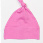 Lyserød babyhue med en knude i toppen ligger fladt på en hvid baggrund. Huen har en simpel, ensartet farve uden mønstre eller dekorationer.