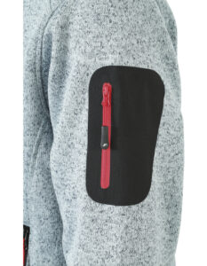 Lomme med en rød lynlås sidder på ærmet af en grå, struktureret trøje. Det sorte stof dækker lommen, der er i casual tøjdesignstil.