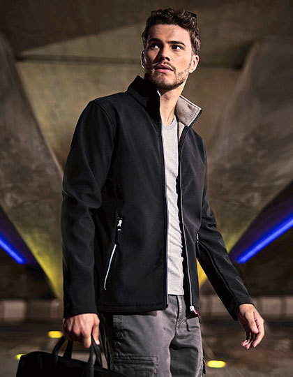 RG762 Mand iført sort jakke står under en buegang, kigger opad. Blåt og gult lys oplyser omgivelserne. Stellen er afslappet og moderne. Ingen tekst til stede.