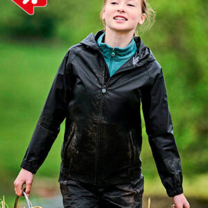 Person iført sort regntøj går udendørs i en grøn, frodig have. Hun bærer en kurv i hånden og ser glad ud.