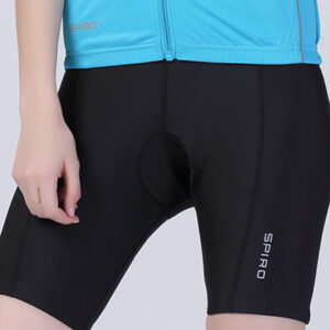 Person iført sorte cykelshorts med teksten "SPIRO" stående. Personen er iført en blå trøje i et neutralt, indendørs miljø.