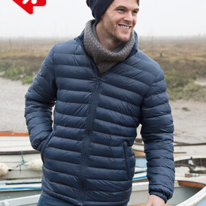 Mand i blå dynejakke og hue smiler, mens han går ved siden af både i et tåget, åbent landskab. Rød grafik i venstre hjørne.