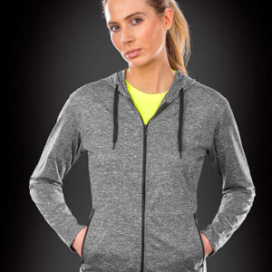 Person iført grå hættetrøje med hænderne i lommerne og lys gul trøje nedenunder, står mod en mørk, gradient baggrund.