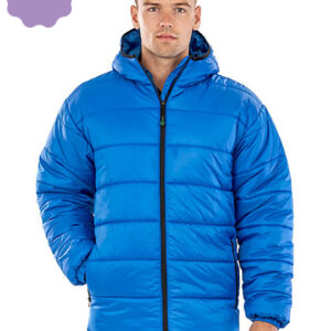 En person iført en blå, foret jakke med hætte står oprejst. Baggrunden er neutral uden synlige detaljer.