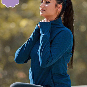 Kvinde i blå trøje strækker sig udendørs i en park, med grønlige træer slørede i baggrunden. Hun er i en koncentreret position og ser opad.