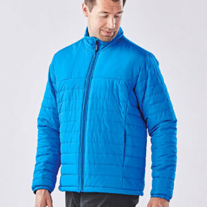 Mand iklædt blå vinterjakke ser til siden. Han står i minimalistisk, lys baggrund uden andre elementer.