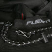 En sort hat med teksten "FLEXFIT" på en elastisk kant, viser en løbesnor med en spænde og en lukkeanordning, placeret i et mørkt, teksturet materiale.